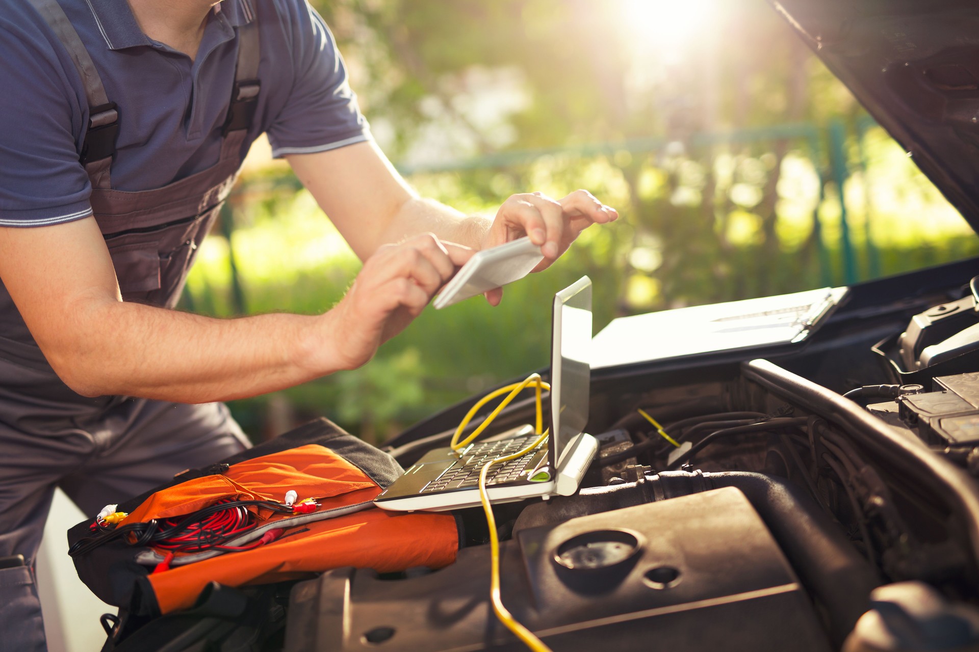 Professional car mechanic using smartphoneto take pictures